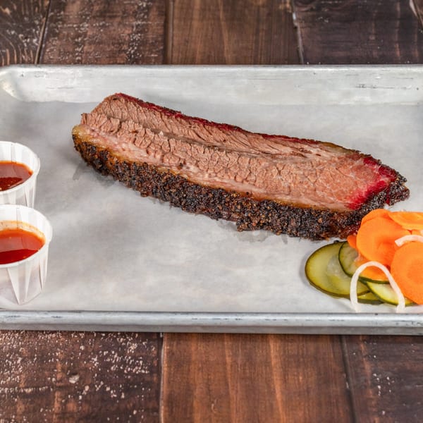 Hattie's BBQ brisket with a smoke ring, two sauces, and pickled carrots, onions, and cucumbers.