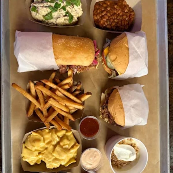A tray of Hattie's BBQ takeout, including sandwiches, fries, mac and cheese, baked beans, and dessert.