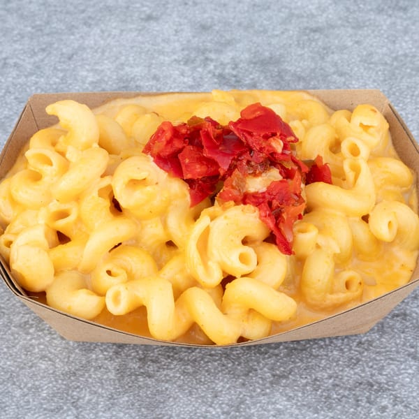 Hattie's BBQ mac and cheese in a brown paper tray, topped with diced red peppers.