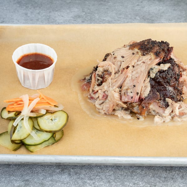 Hattie's BBQ pulled pork with a side of pickles, pickled carrots, and barbecue sauce.