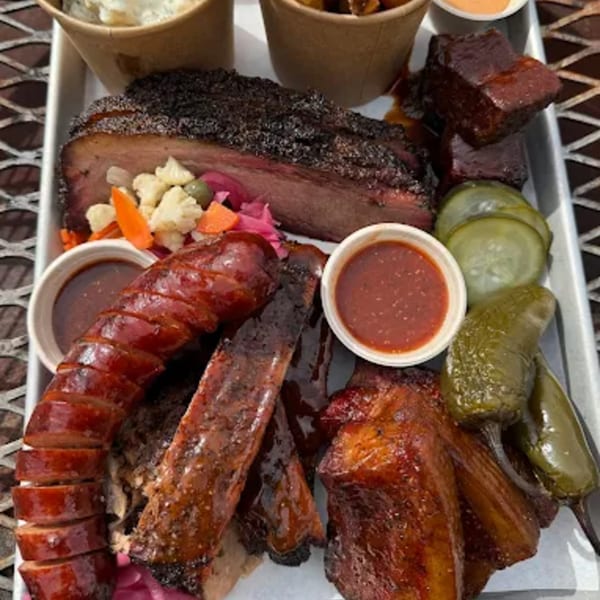 A Hattie's BBQ platter with brisket, sausage, ribs, burnt ends, pickles, pickled vegetables, and sauces.
